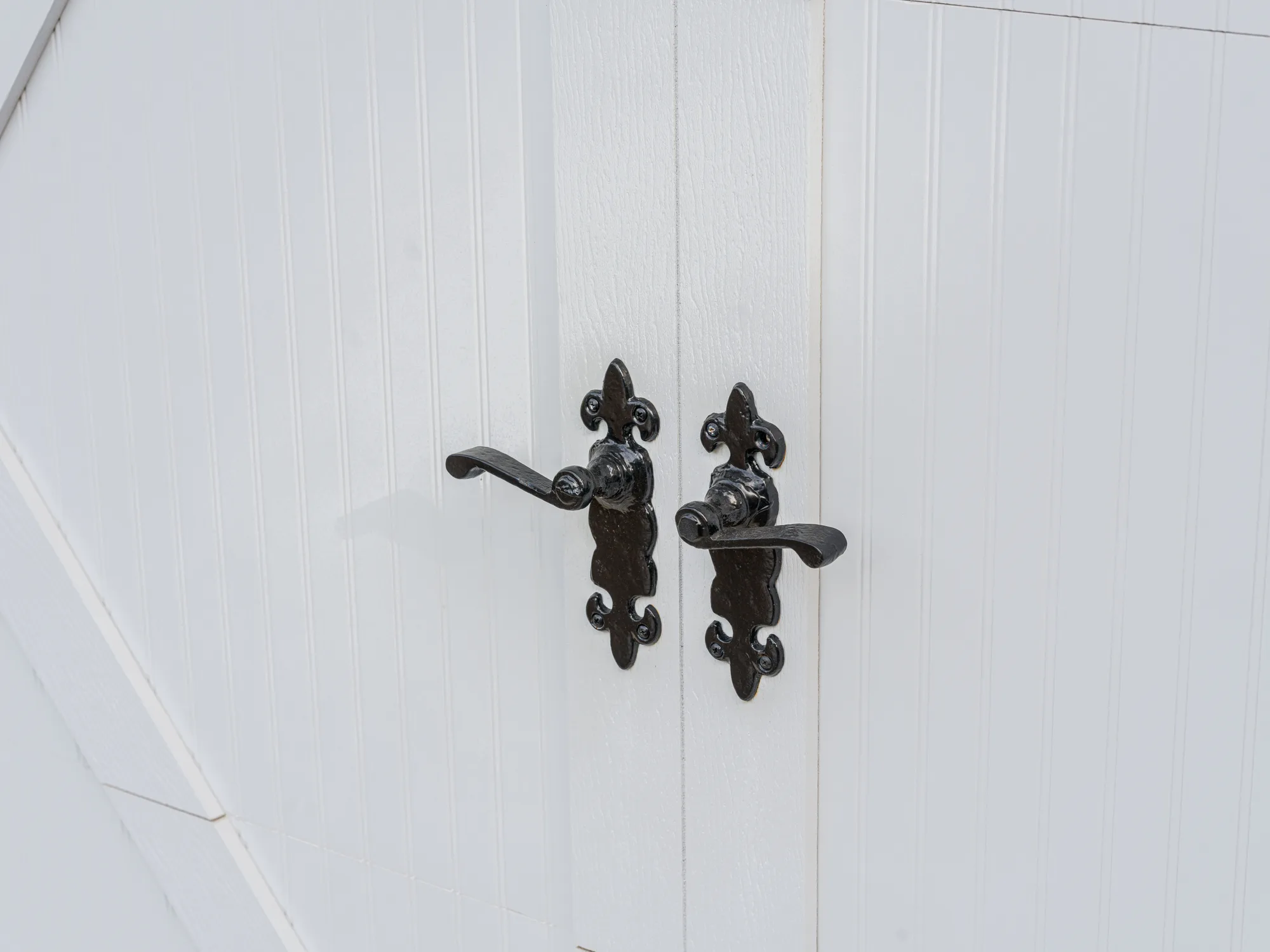 Pair of black decorative handles on a white carriage-style garage door