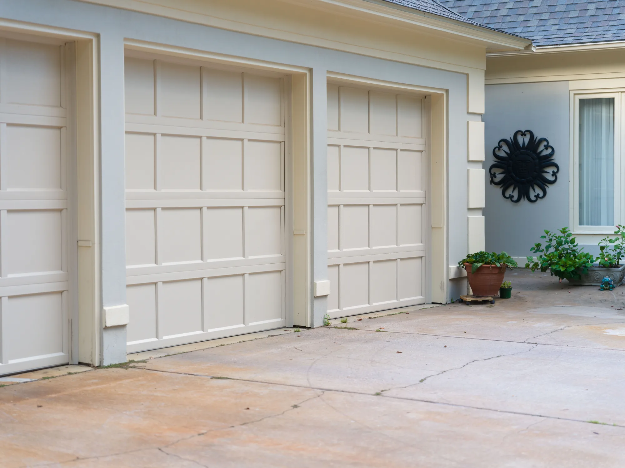 Cream recessed-panel garage doors on a stucco garage, seen at an angle