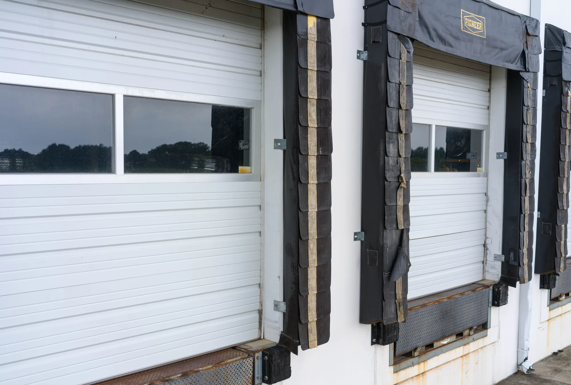 Close view of a loading dock door with a black foam dock seal and a steel leveler plate at the sill