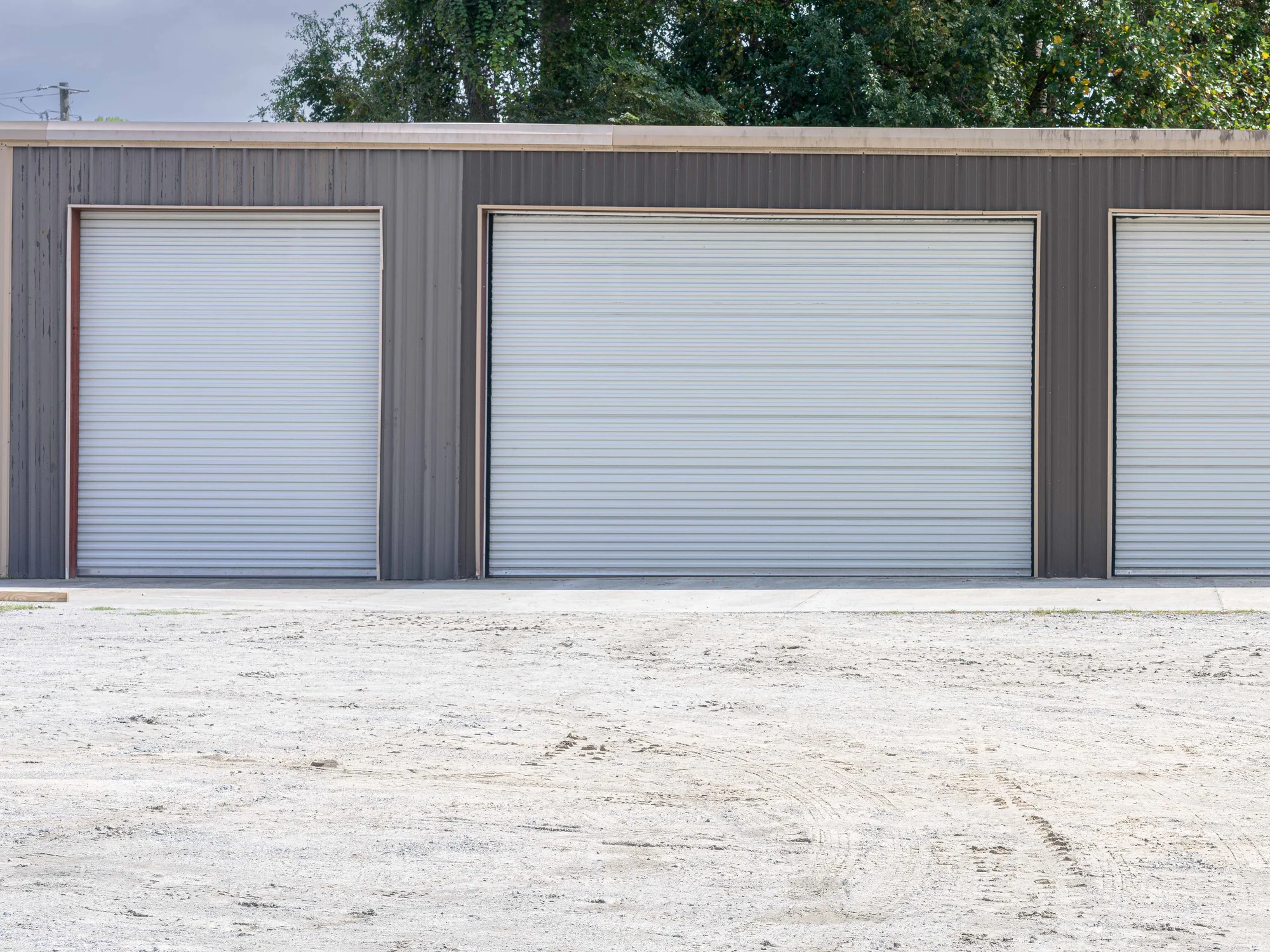 Two white roll-up steel doors on a grey metal storage building