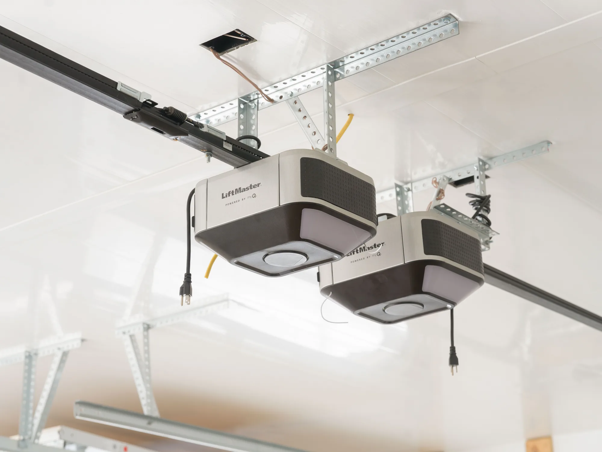 Two LiftMaster garage door openers mounted side by side on a white garage ceiling